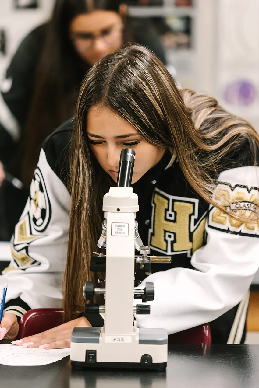 A Heritage student looking through microscope in Chemistry class.